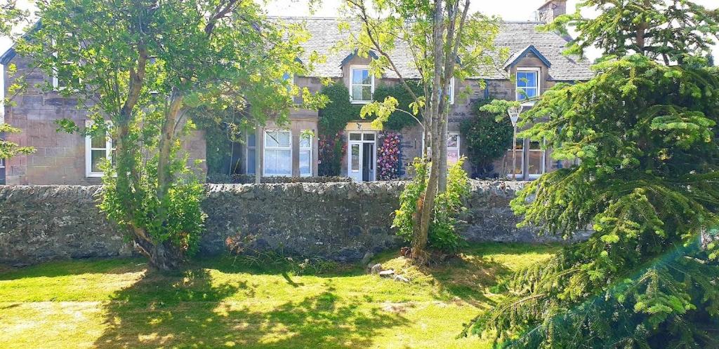 una casa in pietra con alberi di fronte di The Osprey Hotel a Kingussie