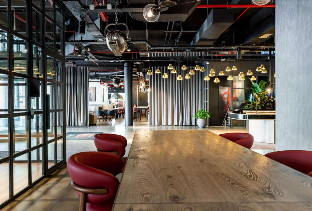 une salle de conférence avec une table en bois et des chaises rouges dans l'établissement Radisson RED Brussels, à Bruxelles