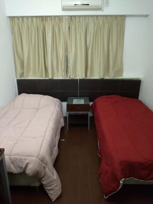 1 dormitorio con 2 camas, mesa y ventana en Comodo departamento en San Nicolas en Buenos Aires
