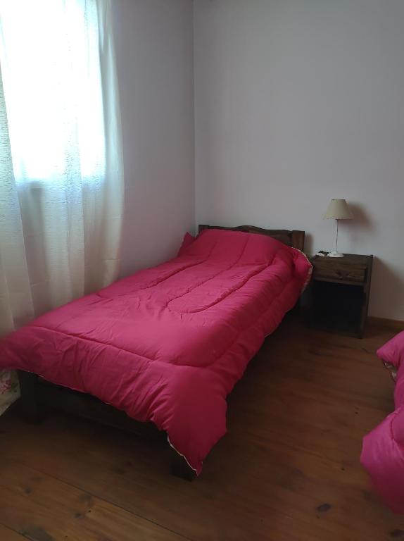 Cama roja en habitación con ventana en Alojamientos Rossi en Malargüe