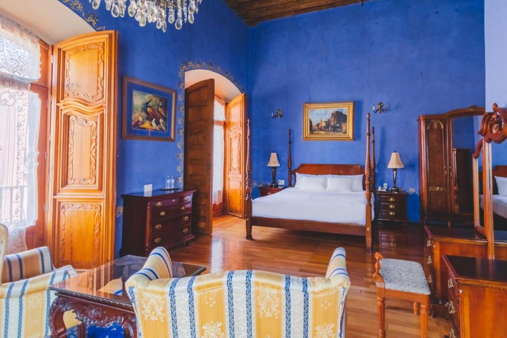 1 dormitorio con paredes azules, 1 cama y sillas en La Casa de la Marquesa en Querétaro