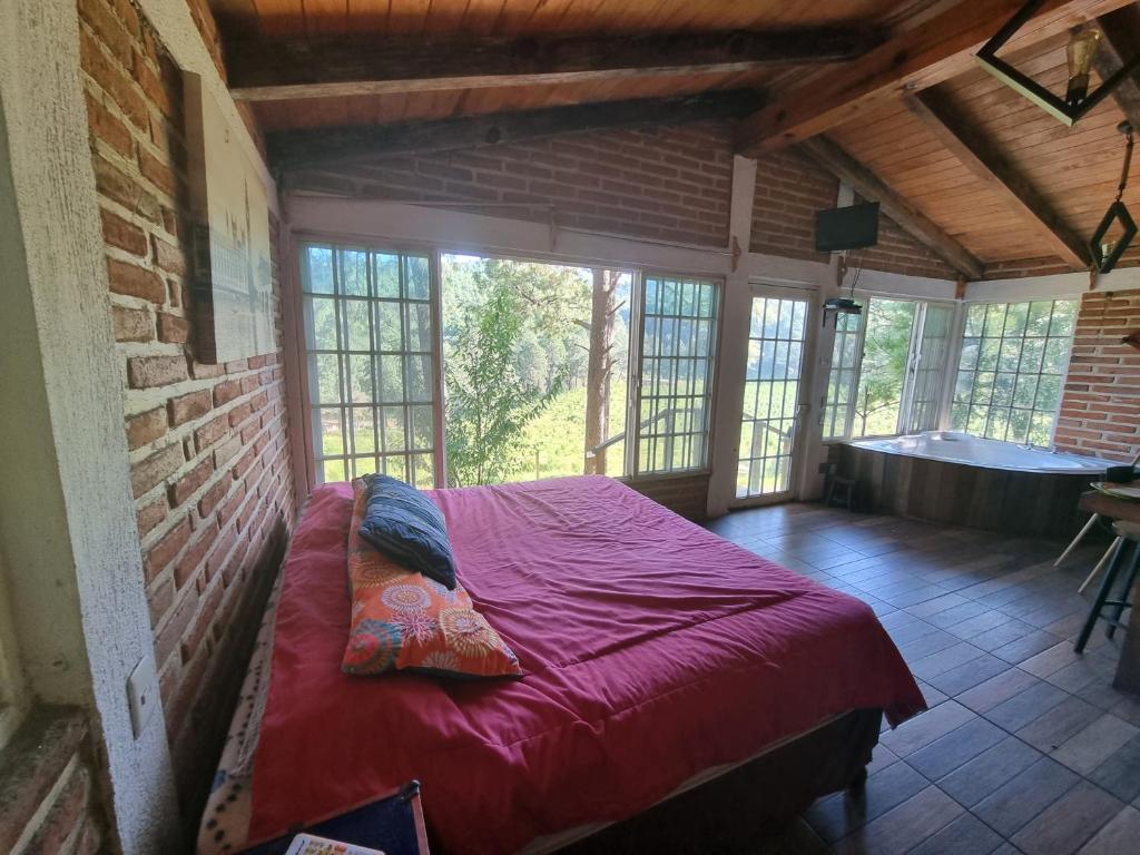 1 dormitorio con 1 cama grande en una habitación con ventanas en Cabañas las Alazanas, en Mazamitla
