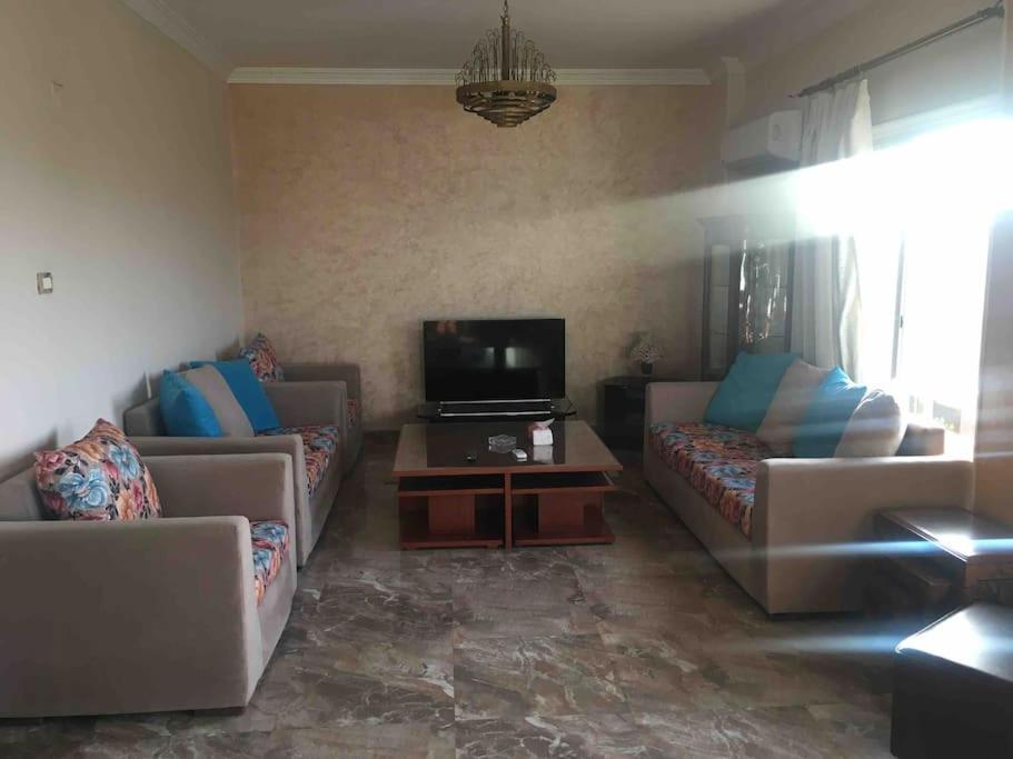 a living room with couches and a flat screen tv at Super Cozy Apt 7 min to CAI in Cairo