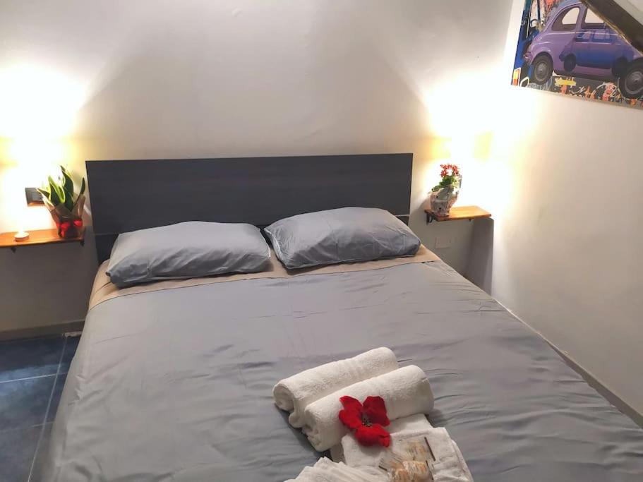 Una cama con toallas y una flor roja. en Kintsugi Loft en Turín