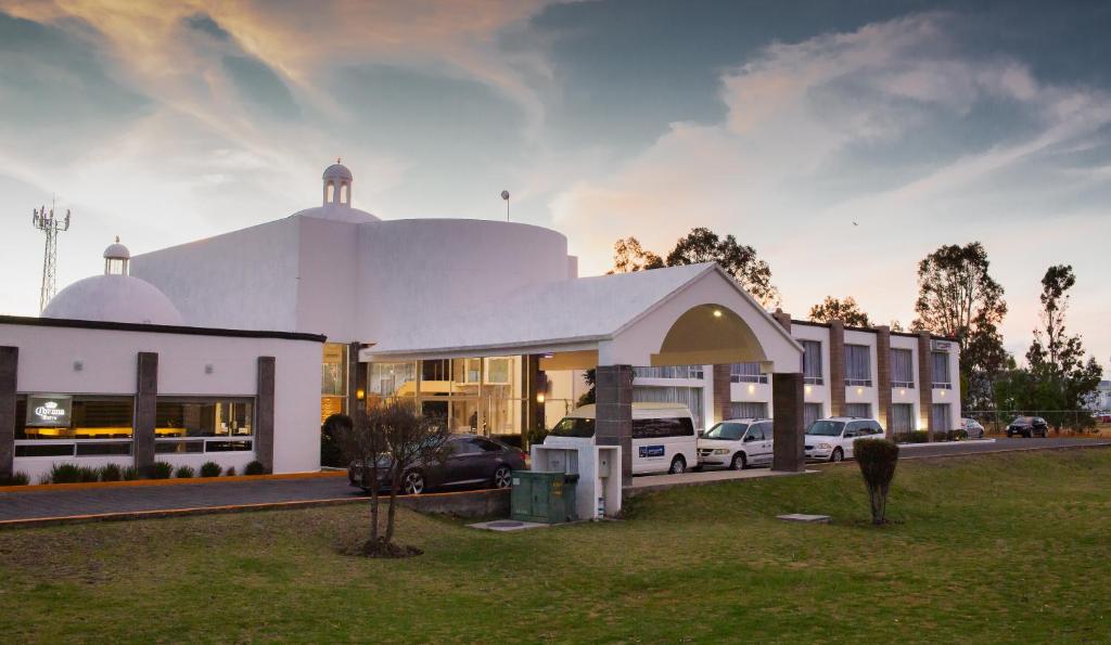 a white building with cars parked in a parking lot at HOTEL AEROPUERTO MORELIA in Álvaro Obregón