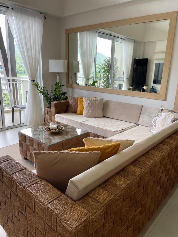 a large couch in a living room with a large mirror at 3BD/3BA Penthouse - Tropical Oasis in Pico de Loro in Patungan