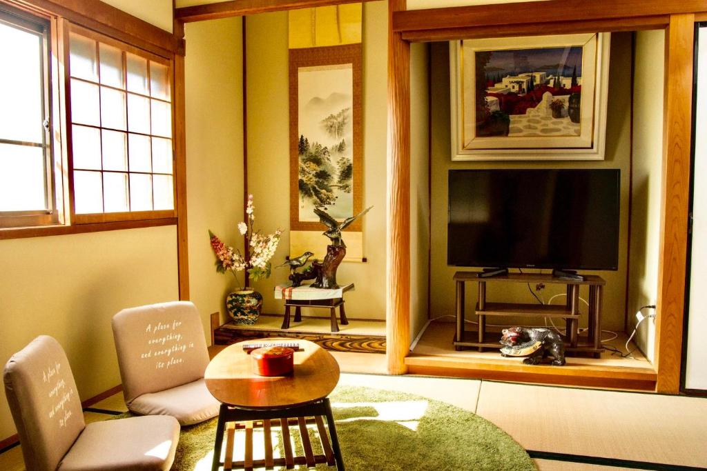 a living room with a television and a table and chairs at 幽舍の庭 in Izumi-Sano