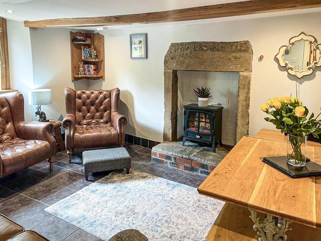 Taddington的住宿－Johnsons Cottage - Uk39727，客厅配有真皮座椅和壁炉