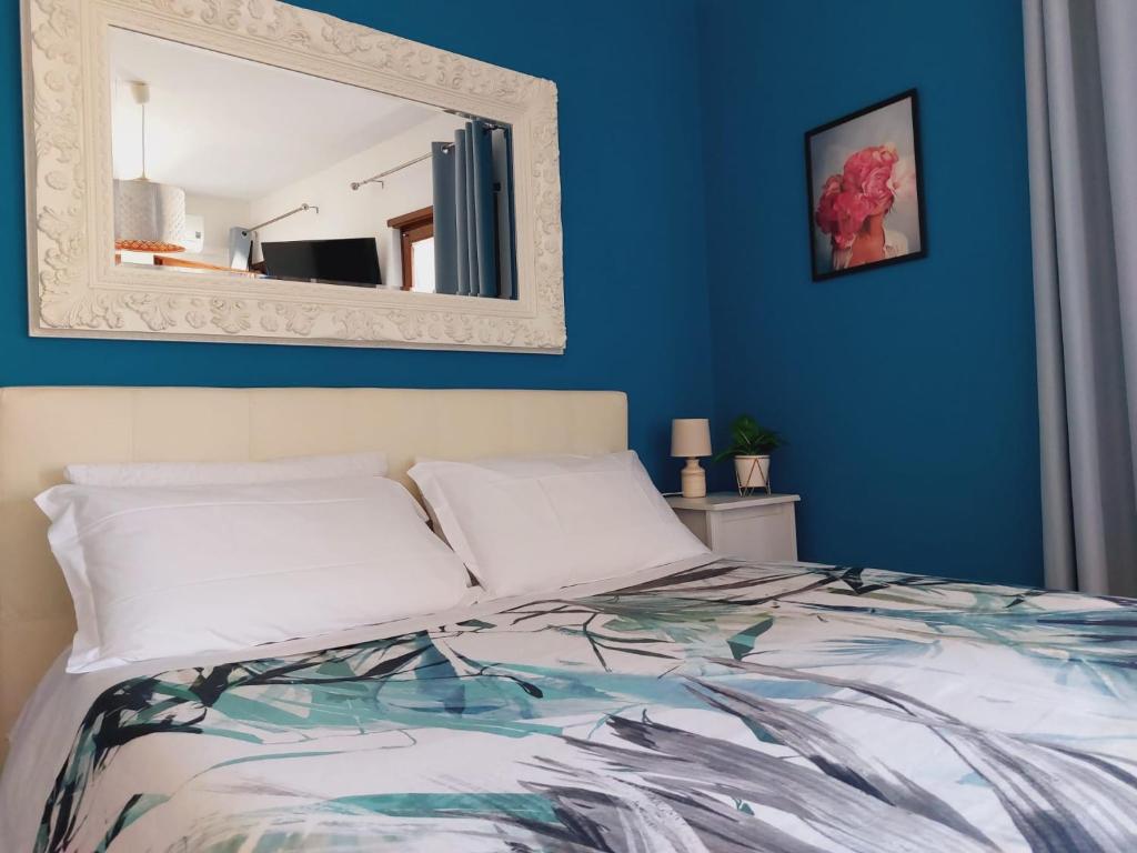 een slaapkamer met blauwe muren en een bed met een spiegel bij Verona Rooms in Verona