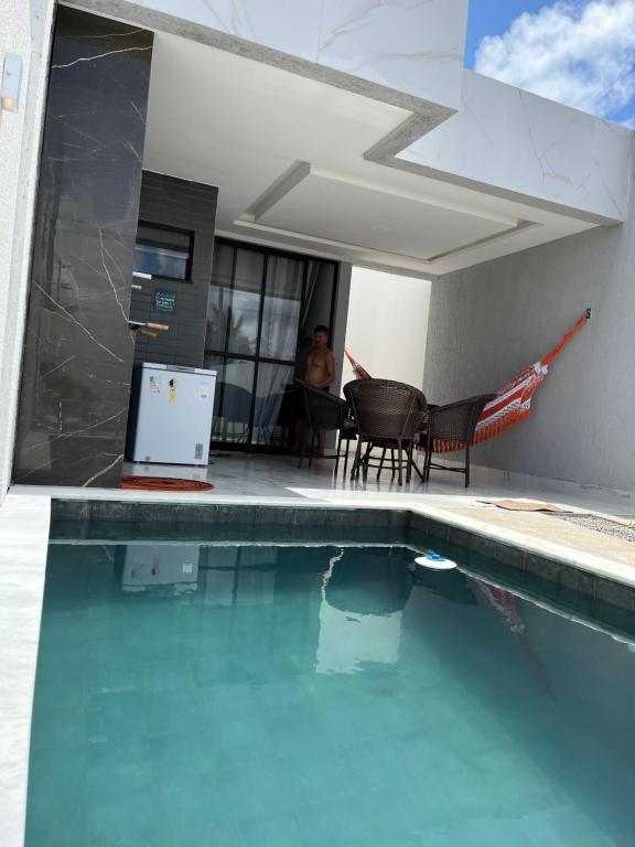 Ein Mann, der an einem Tisch neben einem Pool sitzt. in der Unterkunft Casa da Praia Carapibus in Conde