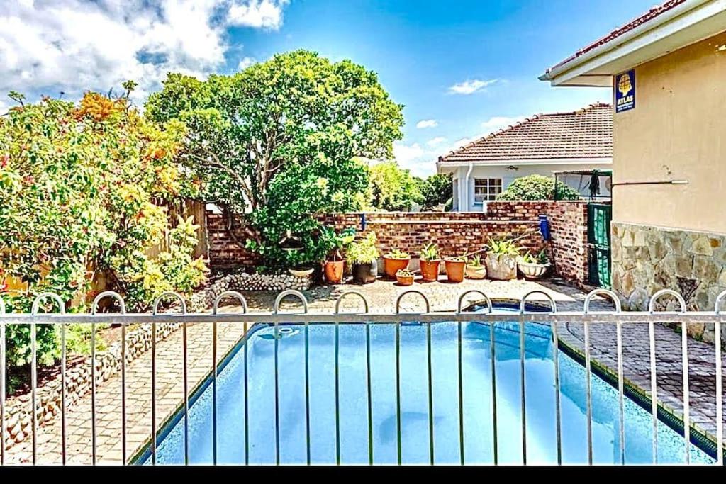 a swimming pool with a fence next to a house at Low budget Cottage- Gqeberha (no loadshedding) in Mount Road