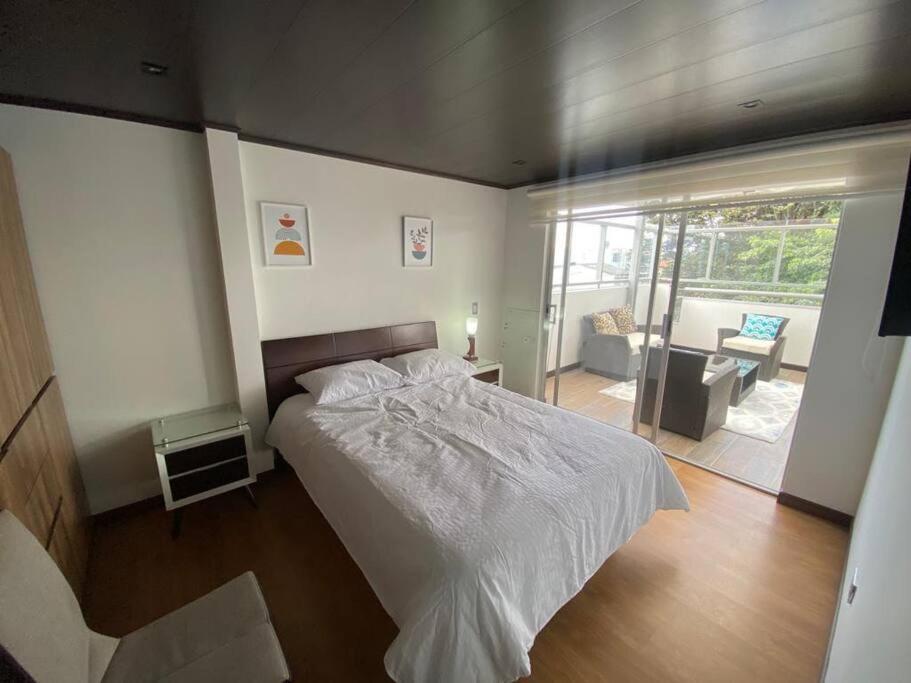 1 dormitorio con cama blanca y balcón en Exelente y acogedora terraza!, en Bogotá