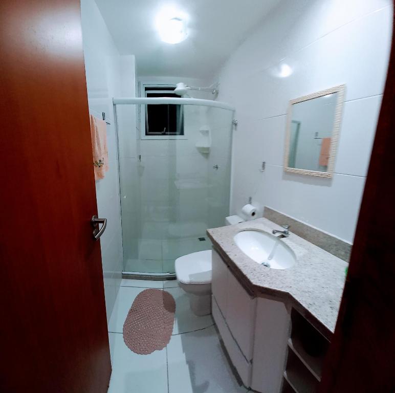 a bathroom with a toilet and a sink and a shower at Apartamento temporada com garagem, Wi-Fi, Netflix in Guarapari