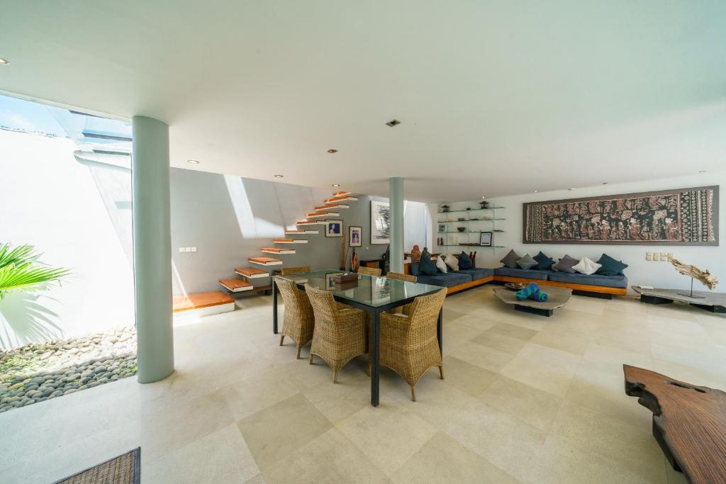 a living room with a table and chairs and a staircase at Villa Rio - Contemporary 2BR Villa in Downtown Seminyak in Seminyak