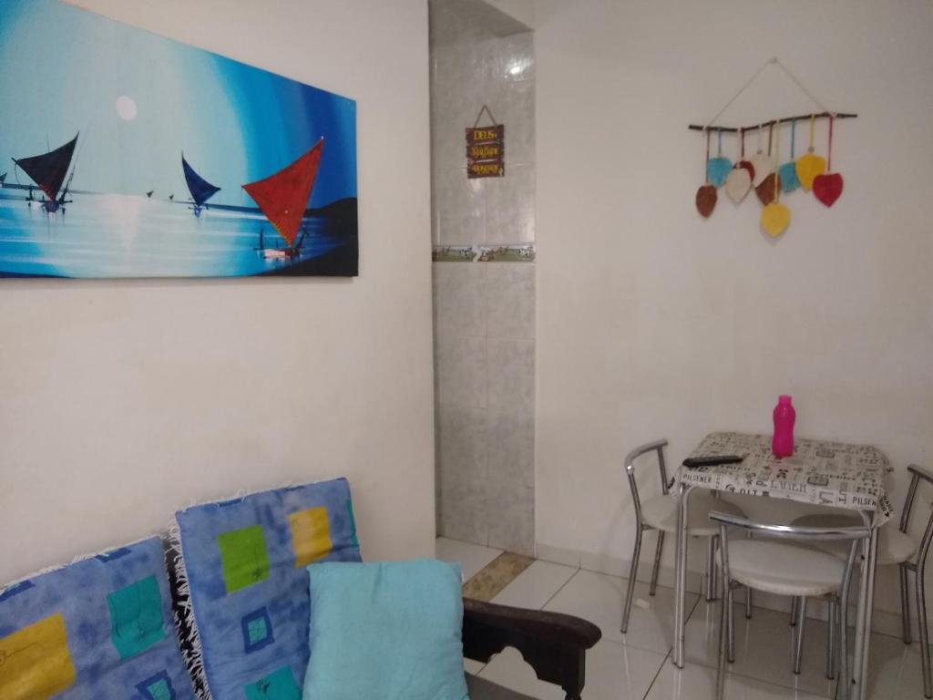 a living room with a table and chairs and a painting at Apartamento de temporada no canto do forte ! in Praia Grande