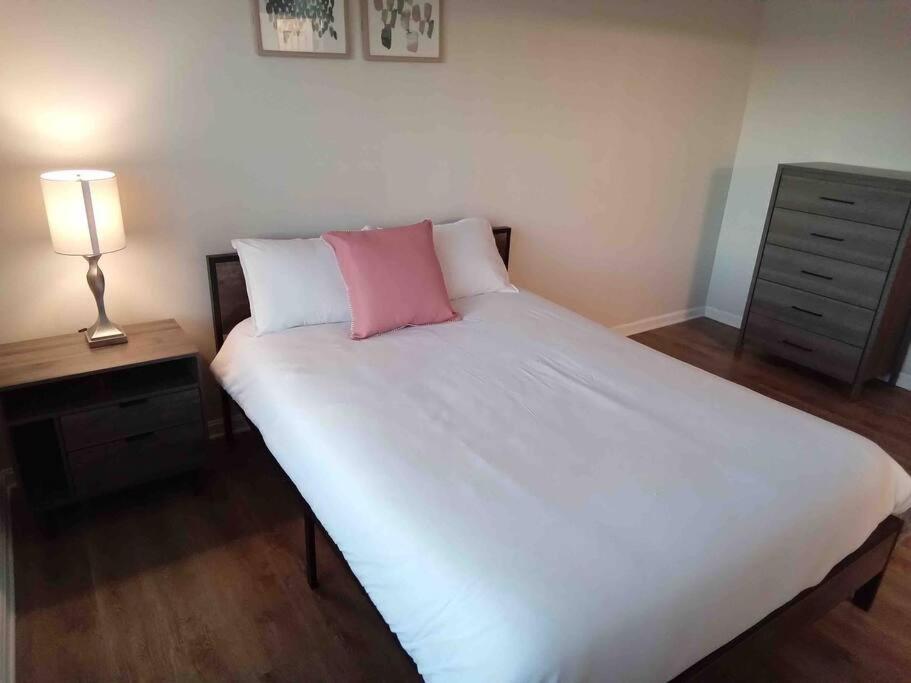 een slaapkamer met een groot wit bed en een roze kussen bij Elegant 4 bedroom house with community pool & deck in Germantown