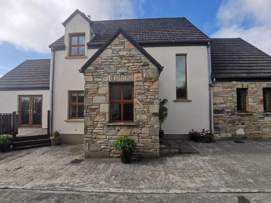 ein weißes Haus mit einem Steingebäude in der Unterkunft Comfortably Crolly Holiday Home in Letterkenny