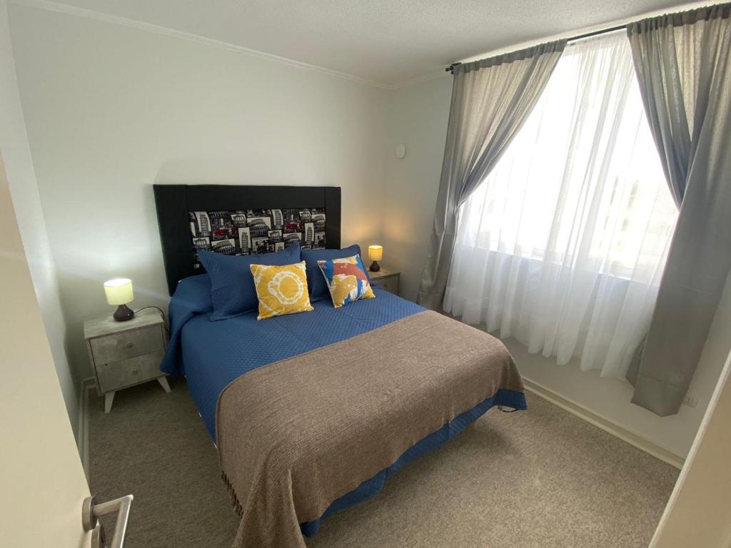 Un dormitorio con una cama azul y una ventana en Fantástico departamento en la Serena al lado de la playa, en La Serena