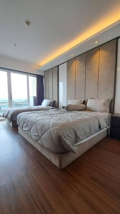 a bedroom with a large bed with a large window at Aston Apartment Batam Floor 21 in Nagoya
