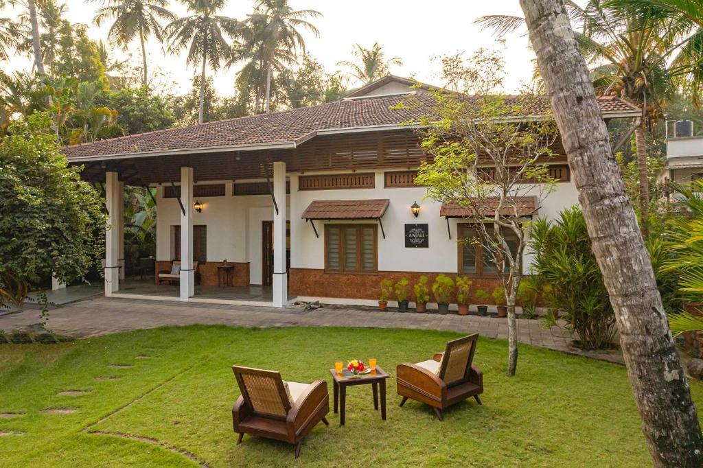 a house with two chairs and a table in the yard at StayVista at Anjali with Complimentary Breakfast & Terrace Access - Big Villa in Kozhikode