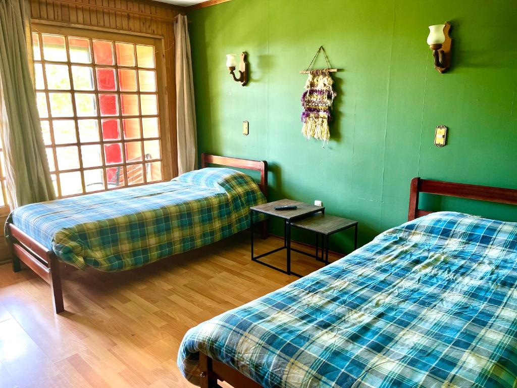 a green room with two beds and a table at Alojamiento 2 camas con baño privado y terraza in Ancud