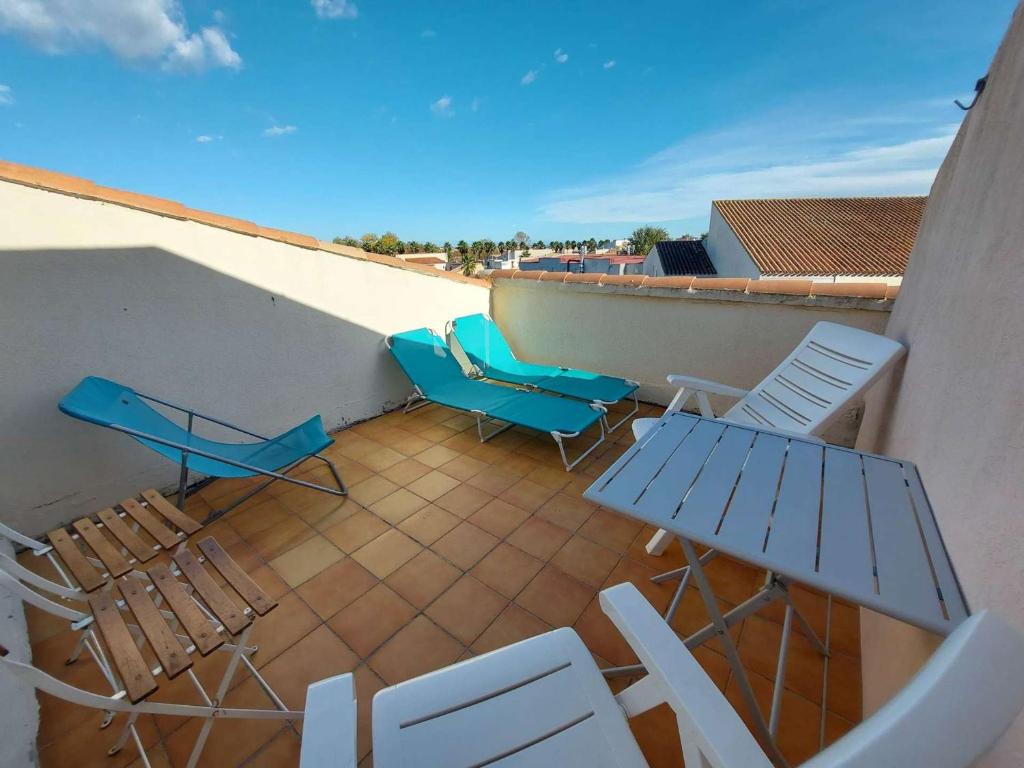 een balkon met stoelen en tafels op een dak bij Appartement Marseillan-Plage, 2 pièces, 5 personnes - FR-1-326-777 in Marseillan