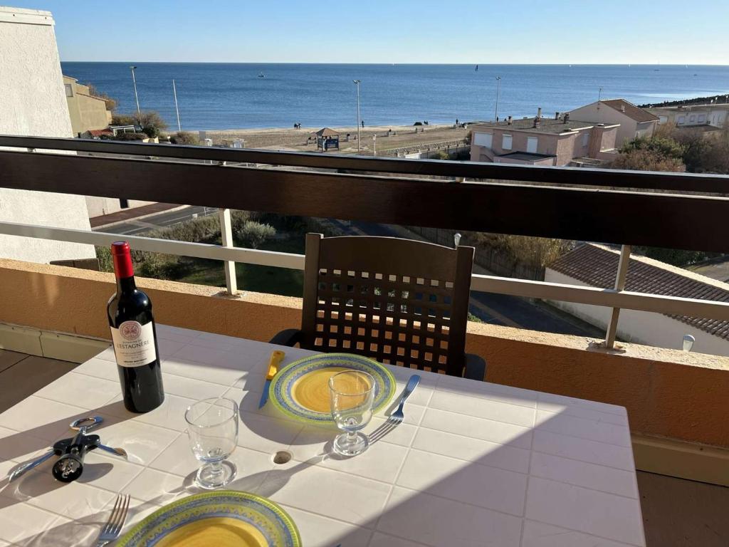 einen Tisch mit einer Flasche Wein und Gläsern auf dem Balkon in der Unterkunft Studio Cap d'Agde, 1 pièce, 4 personnes - FR-1-702-26 in Cap d'Agde