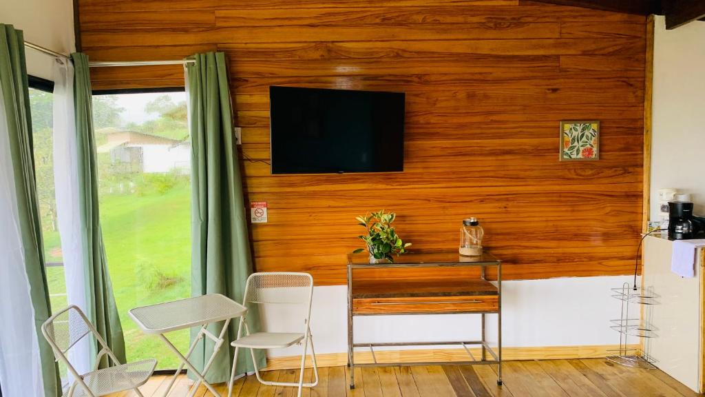 Zimmer mit einem Tisch und einem TV an der Wand in der Unterkunft Cabina Las Nubes in Quesada
