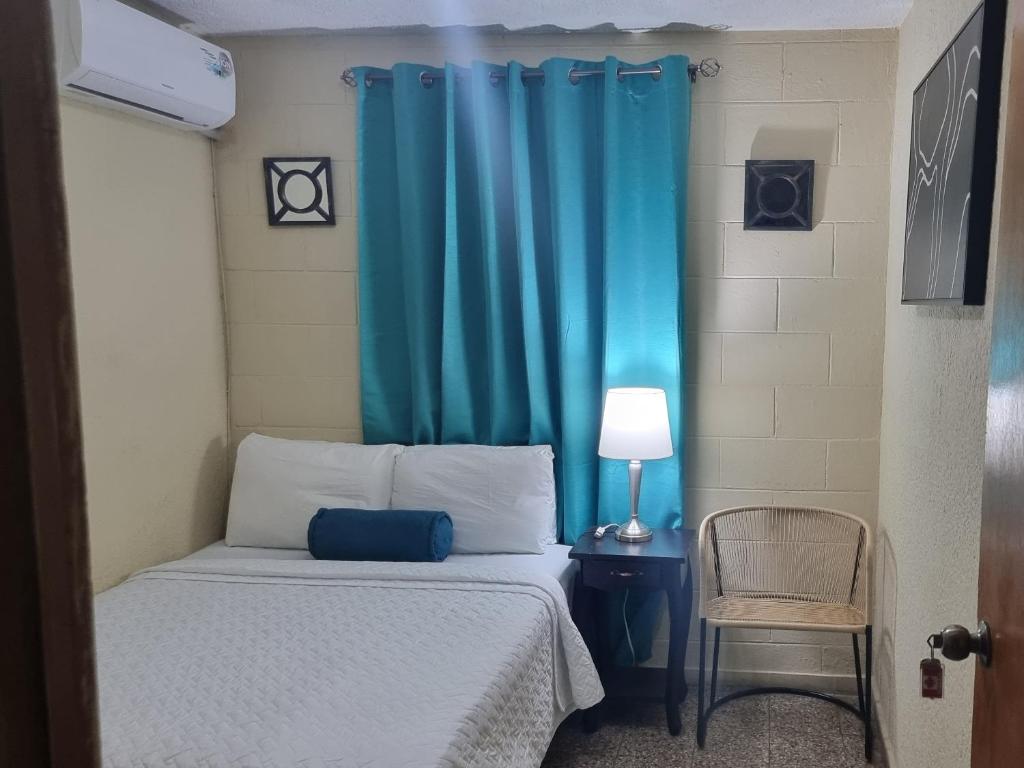 um quarto com uma cama com uma cortina azul em Cat House em Nueva San Salvador