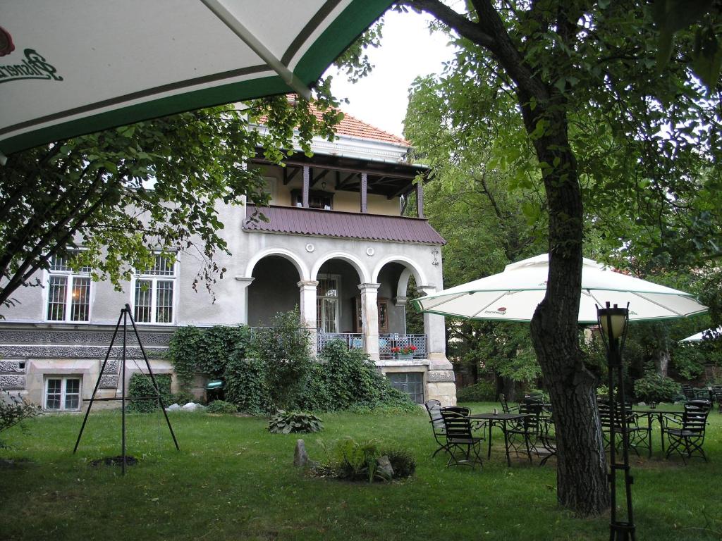 a house with tables and umbrellas in front of it at Willa Wiluszówka in Dębica