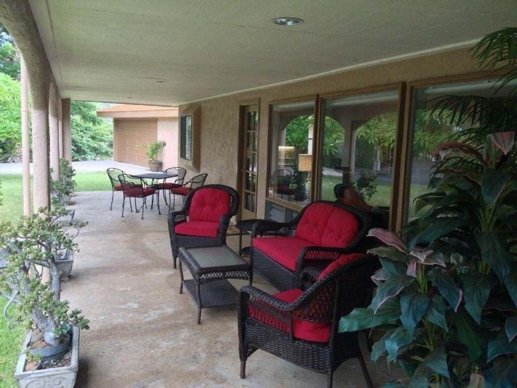 a screened porch with red chairs and a table at Beautiful Spacious Home in Paradise in Waikoloa Village