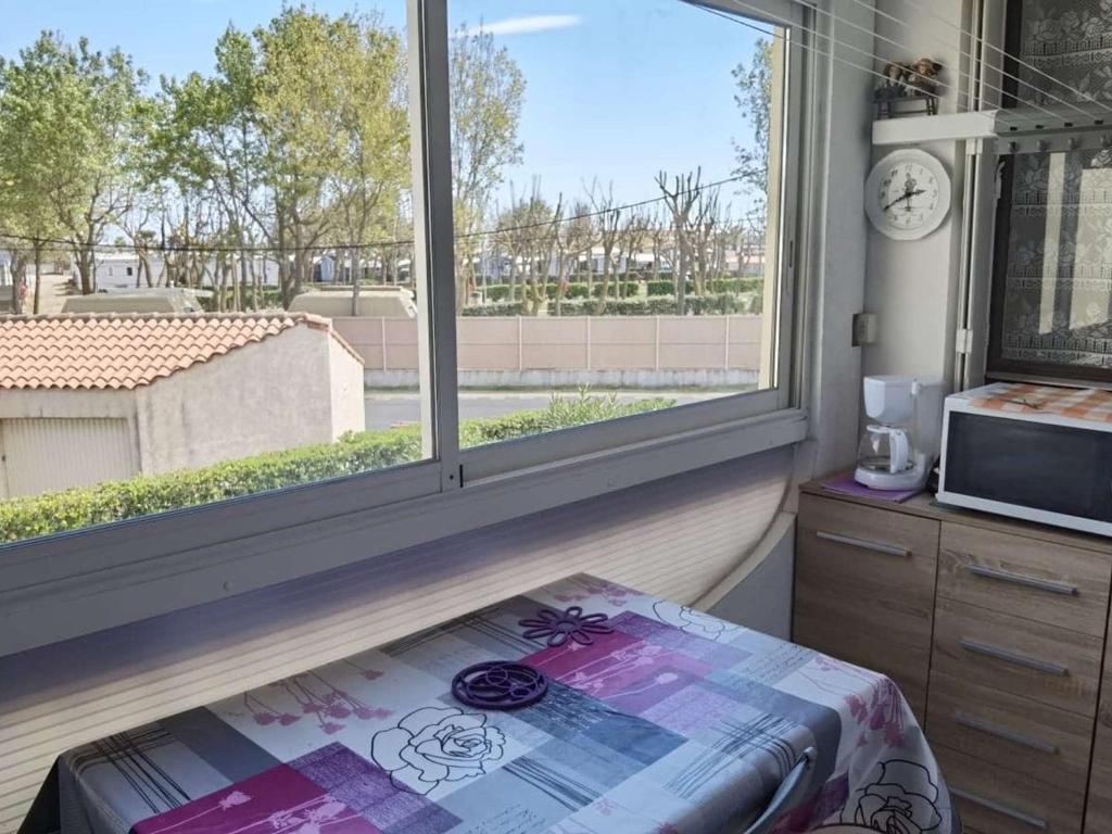 une chambre avec une grande fenêtre et un micro-ondes dans l'établissement Appartement 2 Pièces avec Cabine, Loggia et Parking Privé - 4 Couchages, Marseillan - FR-1-326-723, à Marseillan