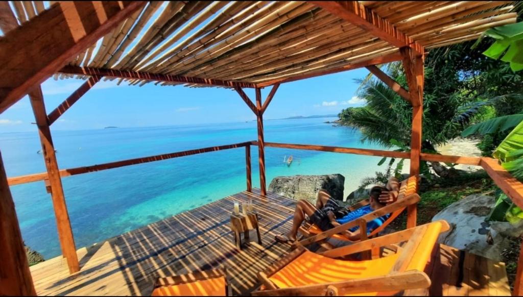 a view of the ocean from a deck with chairs at Villa c'est la vie in Nosy Komba