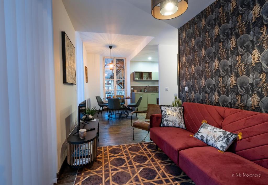 a living room with a red couch and a dining room at Appartement Grenat Bourg d'Oisans in Le Bourg-dʼOisans