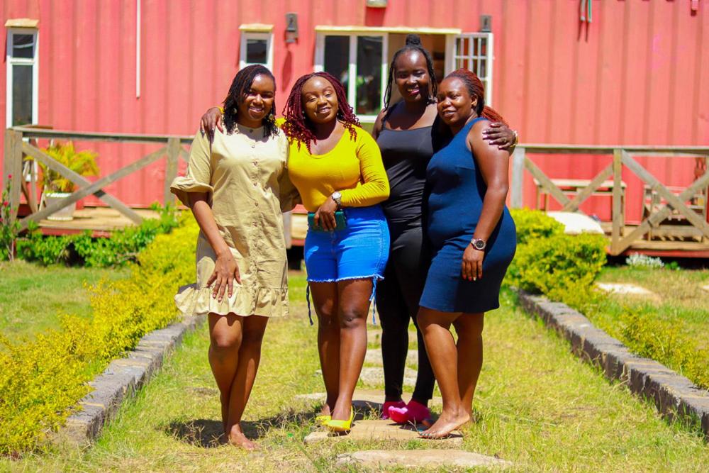 a group of women standing together in front of a red building at The Red Container-Off Grid in Ngong