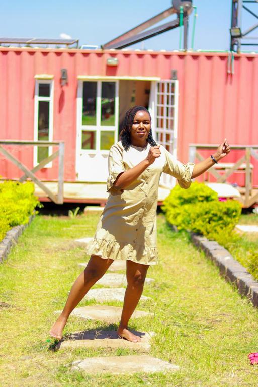 a woman in a dress standing in the grass at The Red Container-Off Grid in Ngong