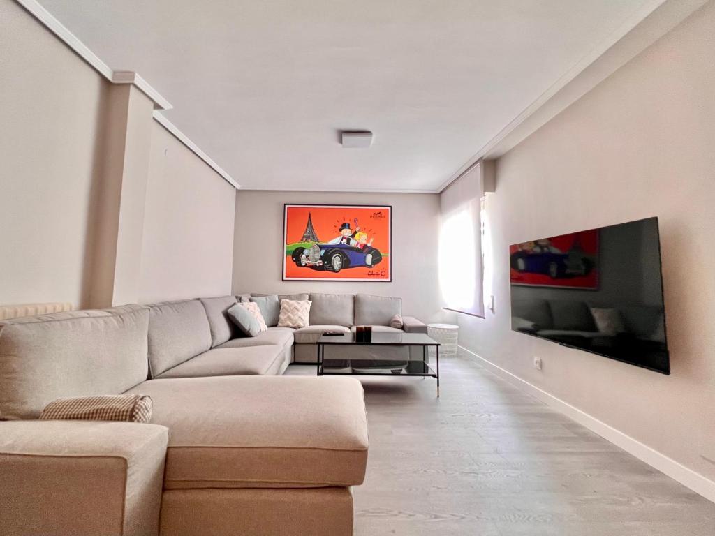 uma sala de estar com um sofá e uma televisão em Housingleon La Paloma em León