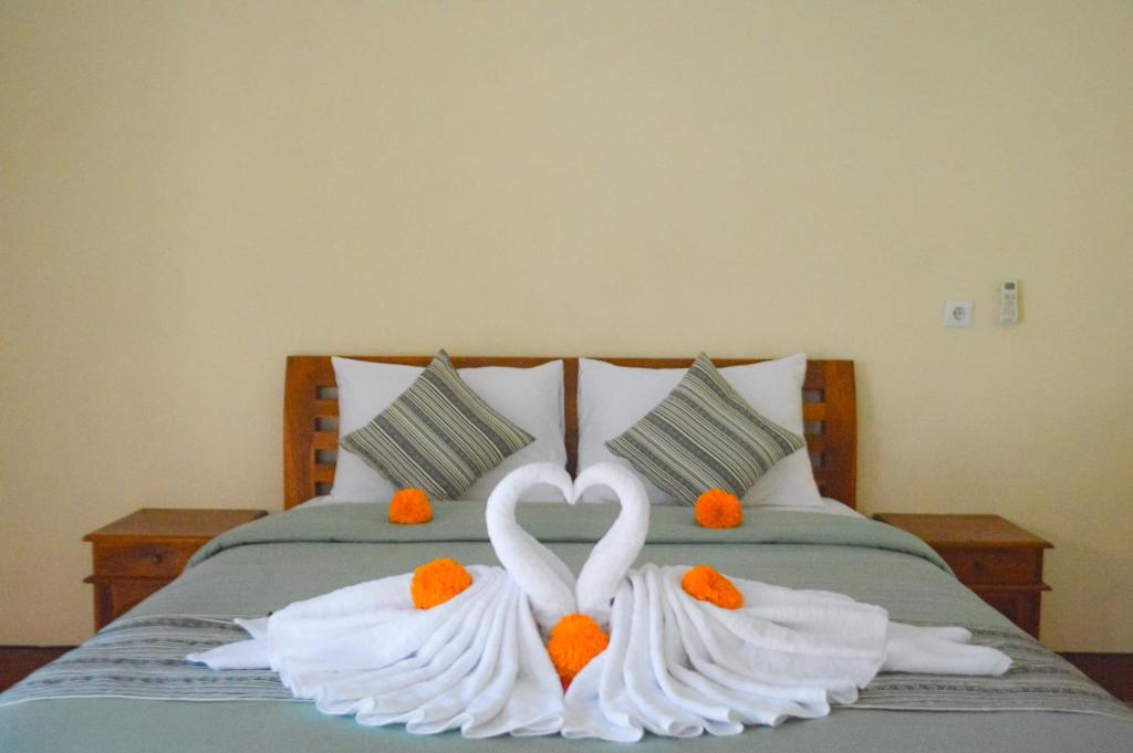 zwei weiße Schwäne machen ein Herz auf einem Bett in der Unterkunft Maja House Penida in Nusa Penida