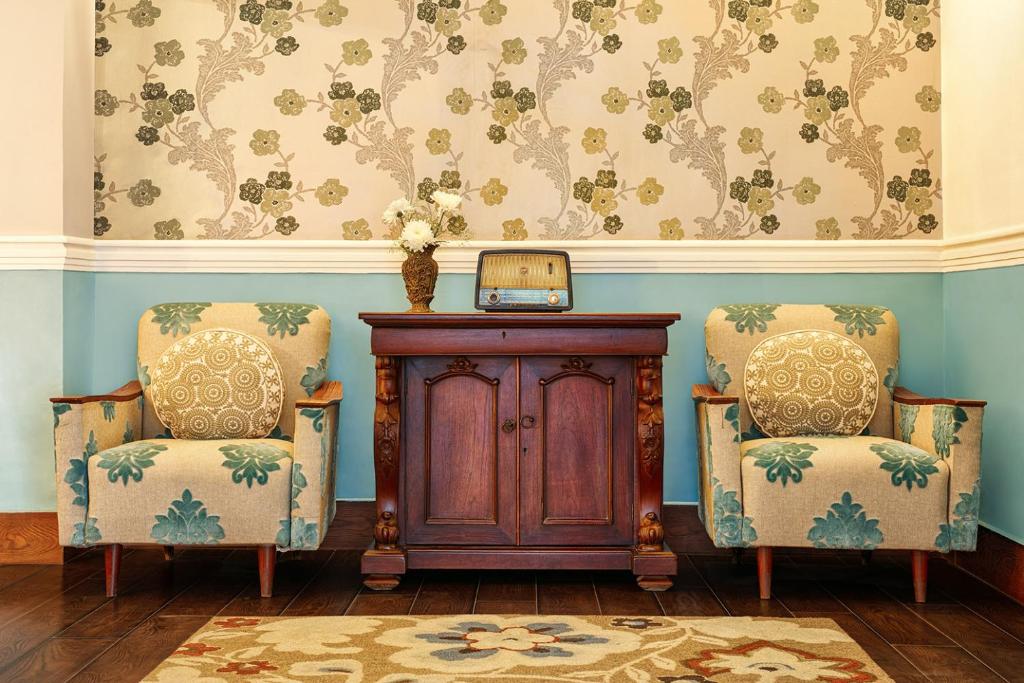 a room with two chairs and a wooden cabinet at Jaagir Manor, Dudhwa - IHCL SeleQtions in Paliā Kalān