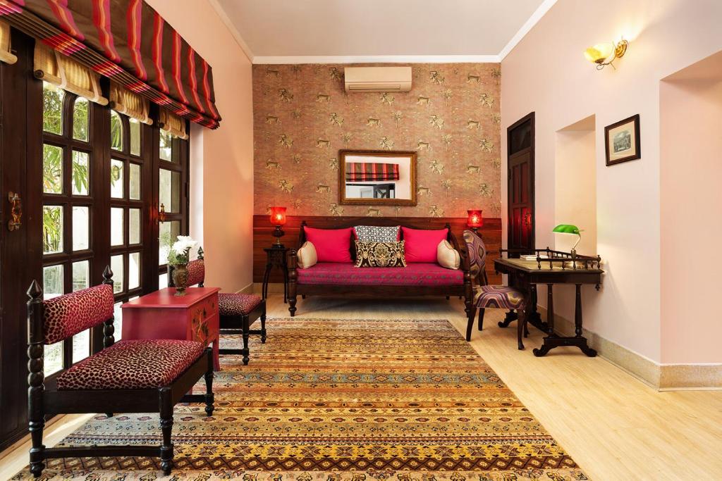 a living room with a red couch and a table at Jaagir Manor, Dudhwa - IHCL SeleQtions in Paliā Kalān
