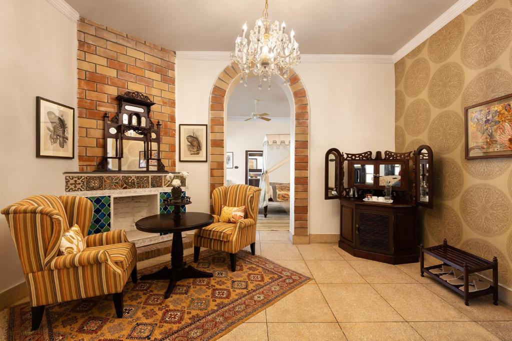 a living room with a fireplace and a table and chairs at Jaagir Manor, Dudhwa - IHCL SeleQtions in Paliā Kalān