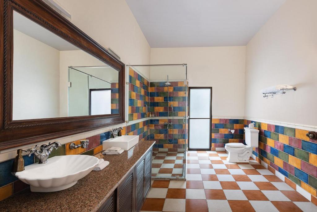 a bathroom with two sinks and a mirror at Jaagir Manor, Dudhwa - IHCL SeleQtions in Paliā Kalān