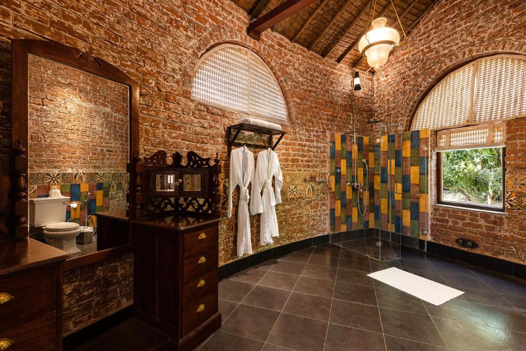 a brick bathroom with a sink and a mirror at Jaagir Manor, Dudhwa - IHCL SeleQtions in Paliā Kalān