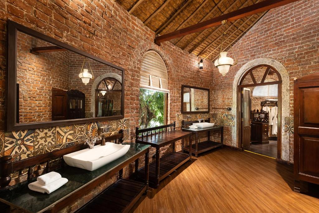 a brick bathroom with two sinks and two mirrors at Jaagir Manor, Dudhwa - IHCL SeleQtions in Paliā Kalān