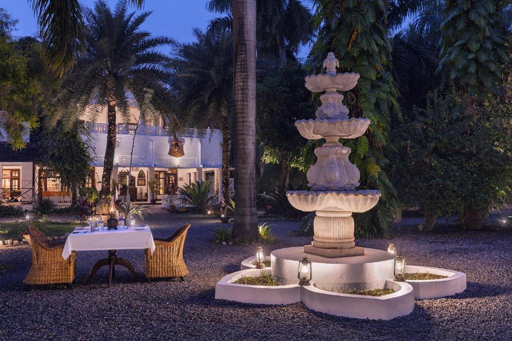 a fountain in a courtyard with a table and chairs at Jaagir Manor, Dudhwa - IHCL SeleQtions in Paliā Kalān