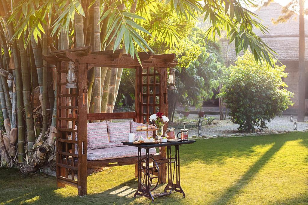 a wooden pergola with a bench and a table at Jaagir Manor, Dudhwa - IHCL SeleQtions in Paliā Kalān