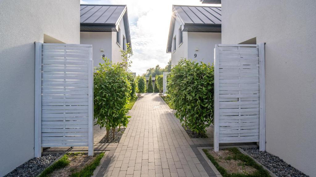 an empty alley between two white buildings with trees at Turkusowy Klif in Jastrzębia Góra