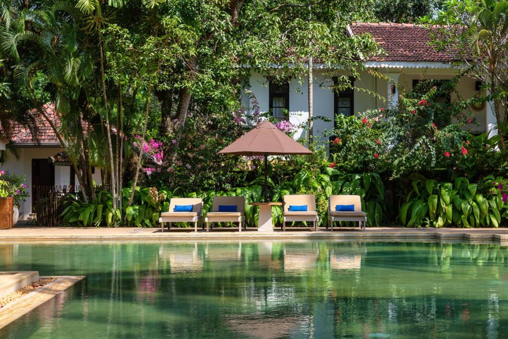 two chairs and an umbrella next to a swimming pool at Why House in Unawatuna