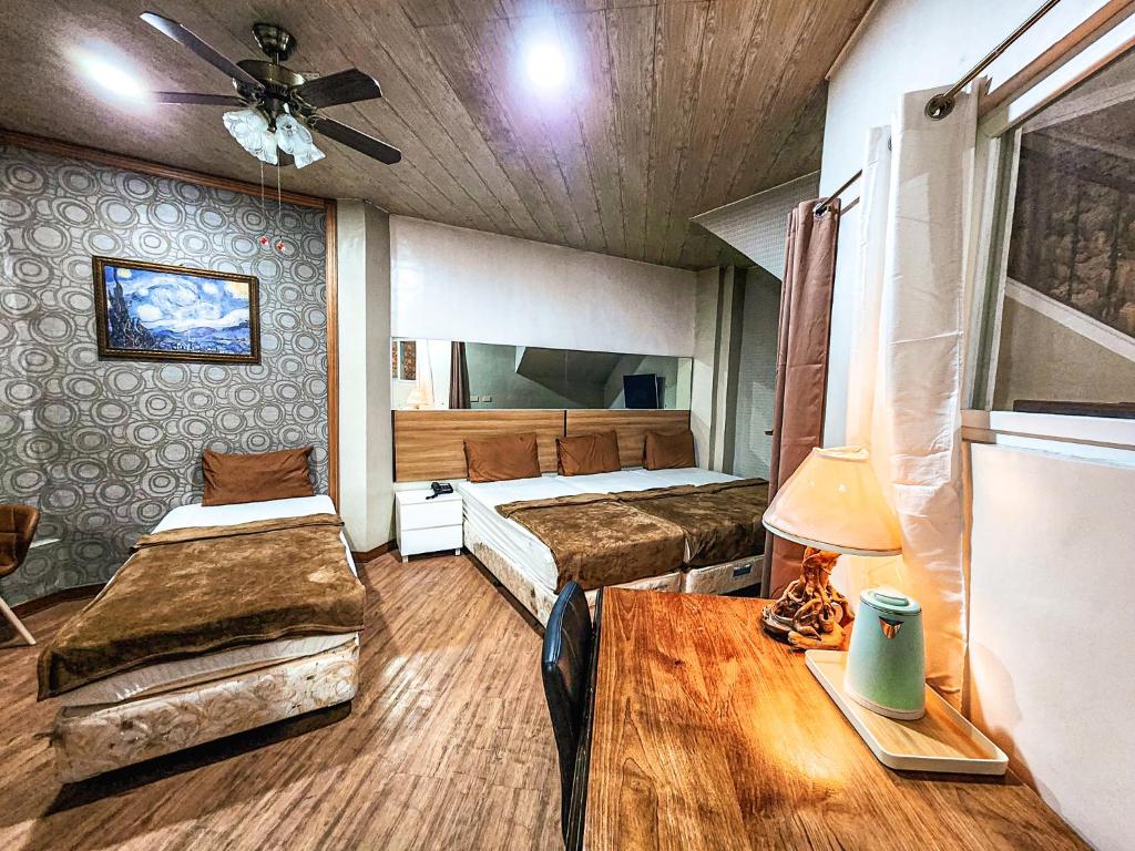 a bedroom with two beds and a table in it at Hotel Urban in Baguio