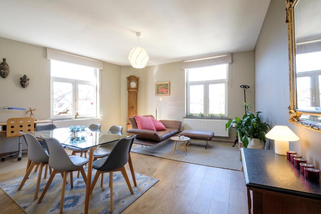 ein Wohnzimmer mit einem Tisch, Stühlen und einem Sofa in der Unterkunft Charmant Appartement 1 chambre avec balcon proximité Cinquantenaire in Brüssel